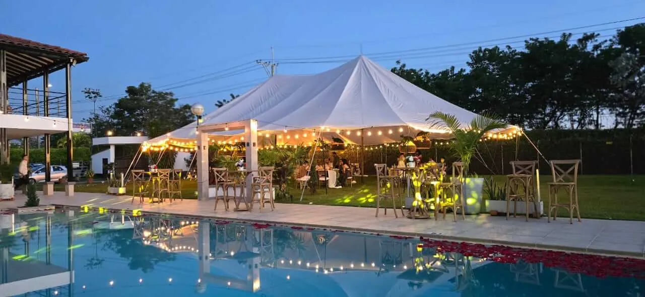 Recepción de matrimonio con carpa, luces cálidas y piscina en finca del Eje Cafetero